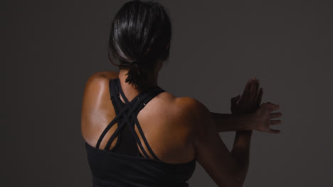 Close-Up-Studio-Shot-Showing-Back-Of-Mature-Woman-Wearing-Gym-Fitness-Clothing-Doing-Stretching-Exercises-3